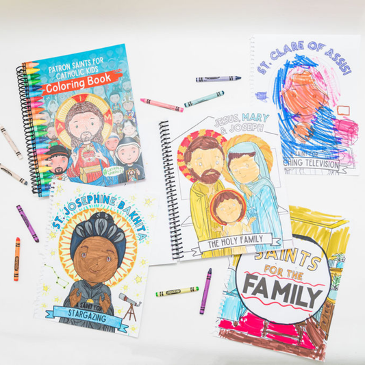 Coloring books and crayons on a white surface with religious illustrations.