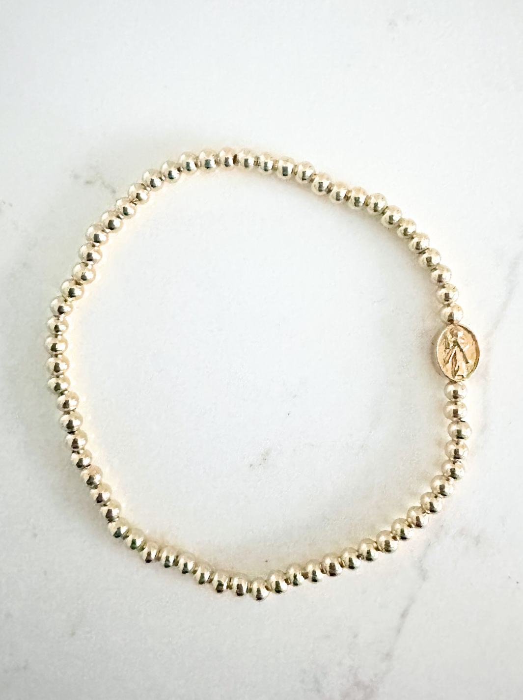 Gold beaded bracelet on a light marble background