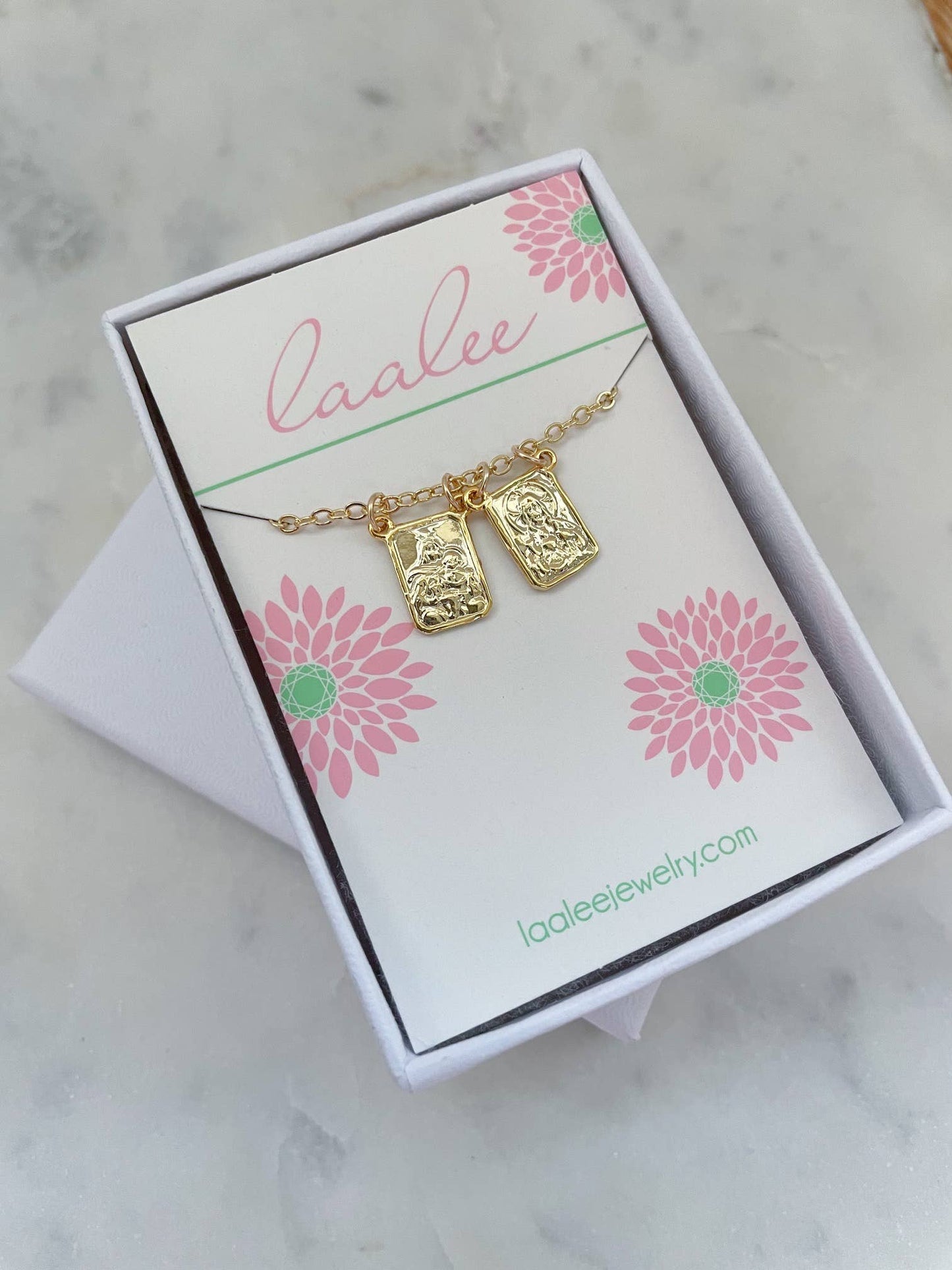 Gold necklace with pendant on a 'Laalee' branded card with floral designs.