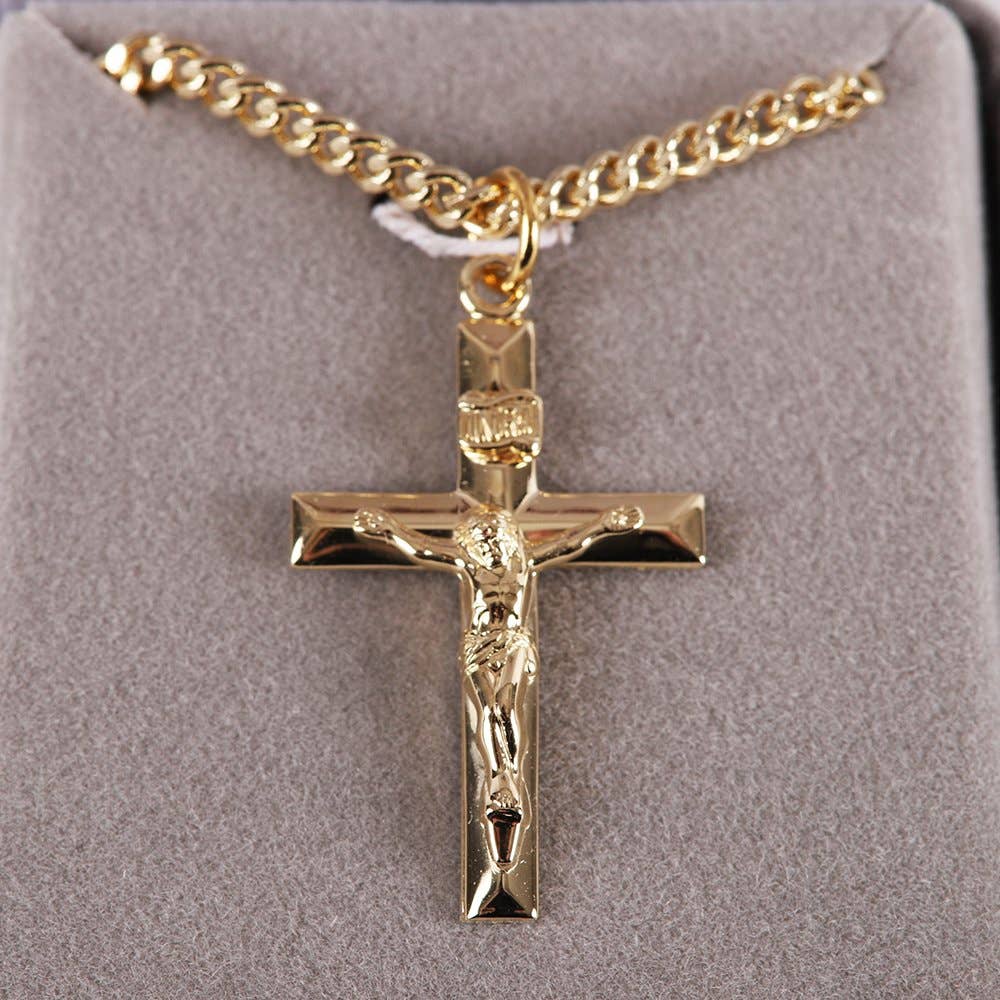 Gold crucifix pendant on a gold chain against a gray background