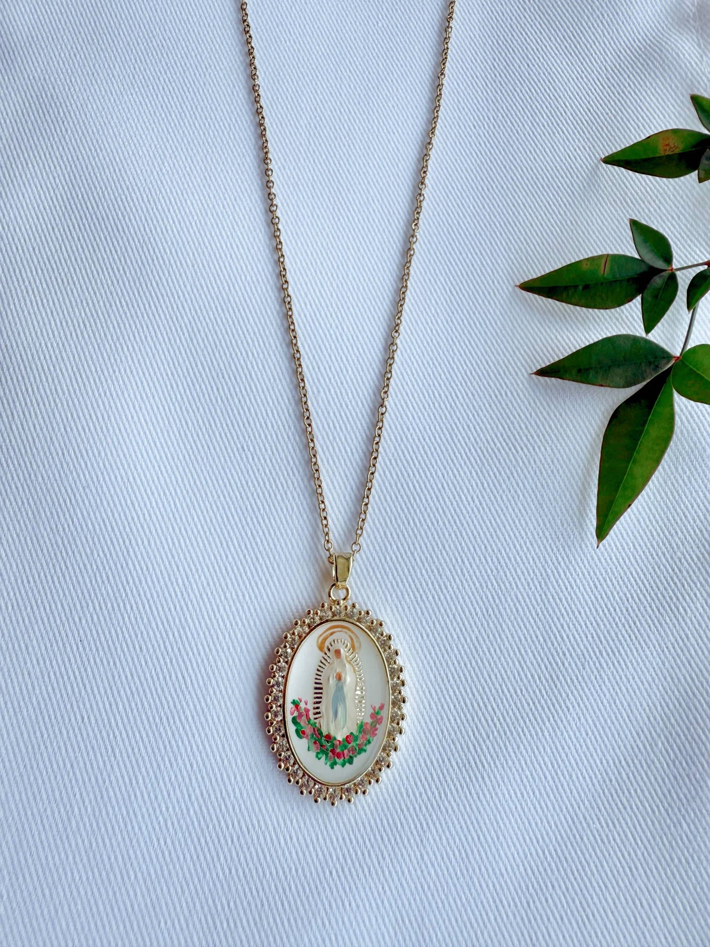 Necklace with a pendant featuring a religious design on a light blue fabric background.