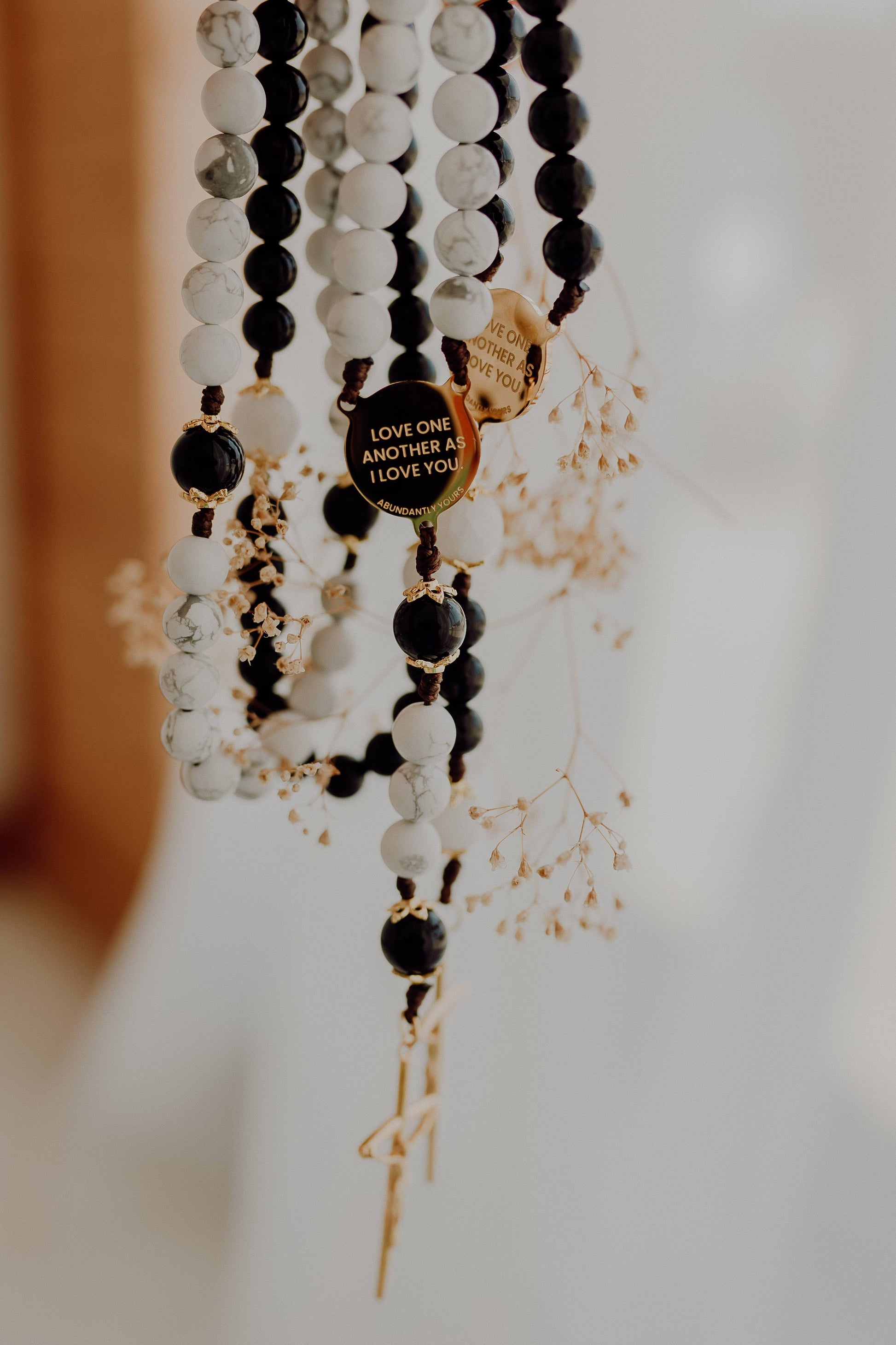 Black, white, and gold beaded rosary’s with a heart-shaped pendant on a blurred background