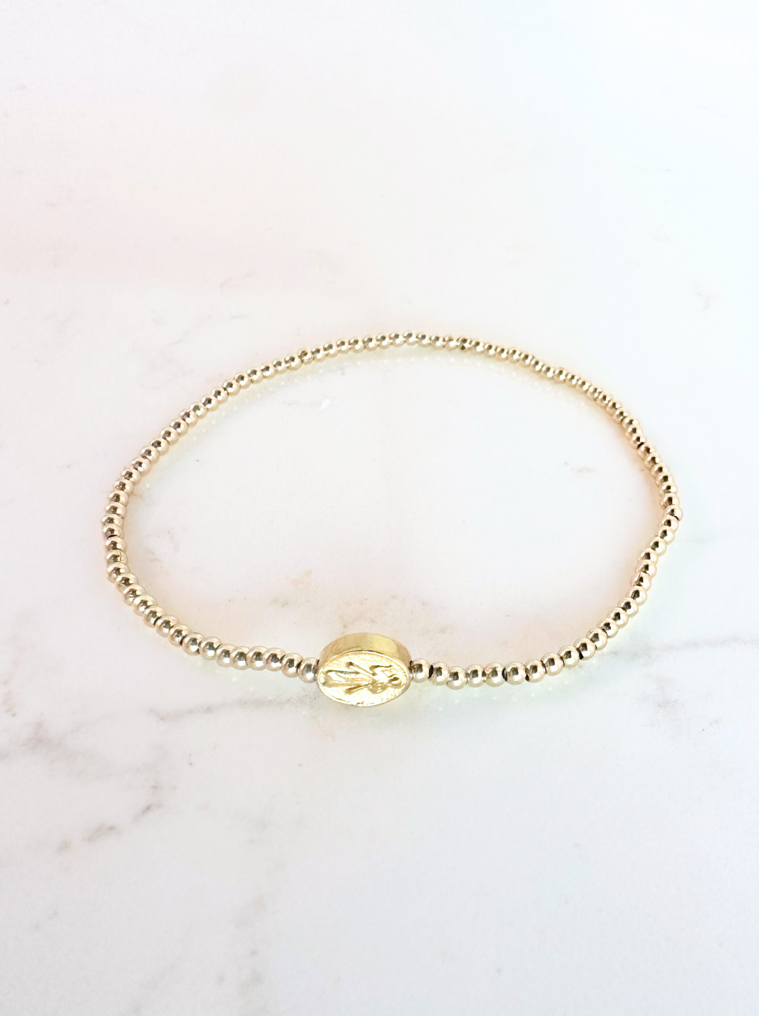 Gold bracelet on a light pink marble background