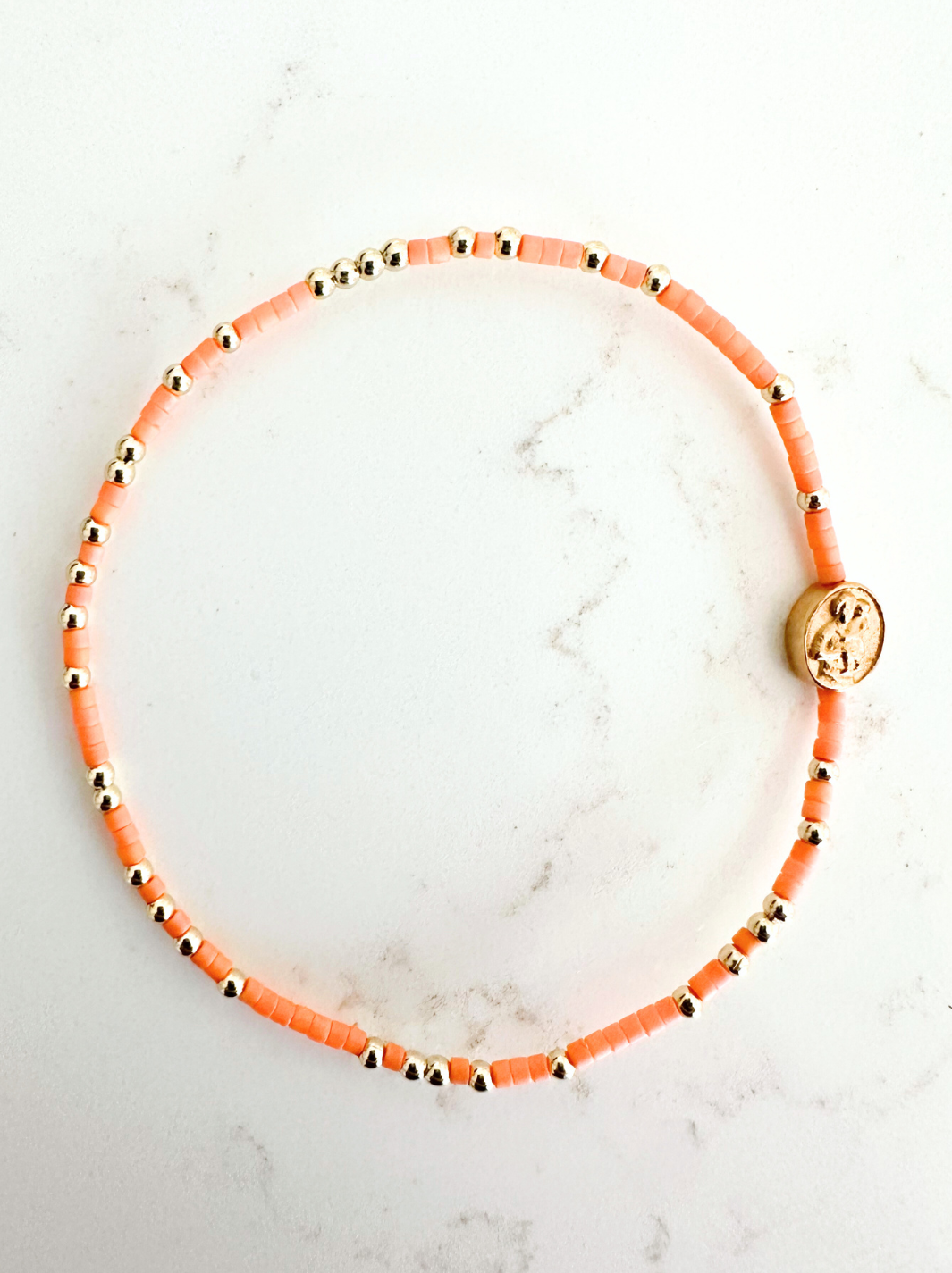 Bracelet with orange beads on a marble surface