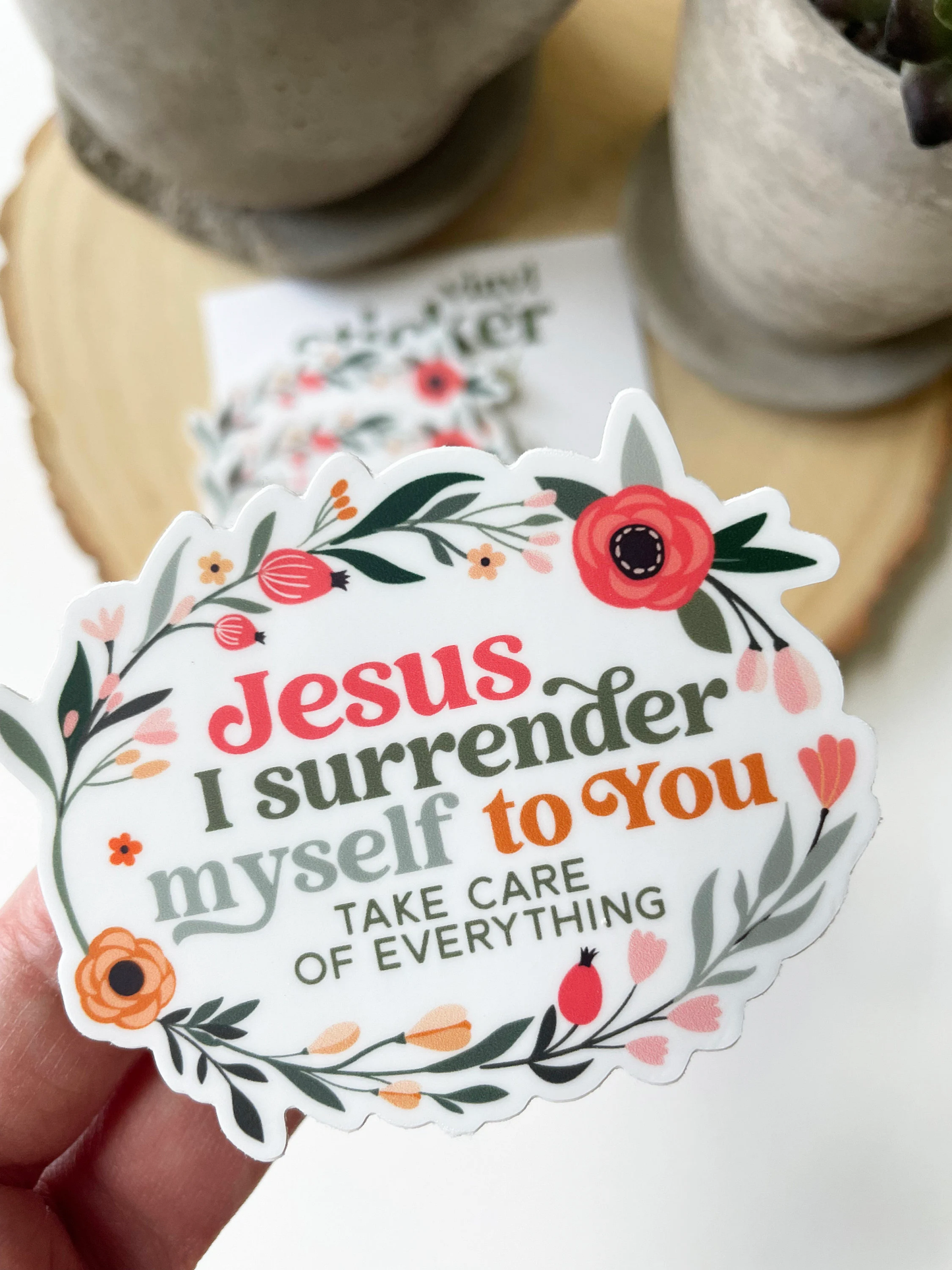 Decorative sticker with floral design and text held by a hand