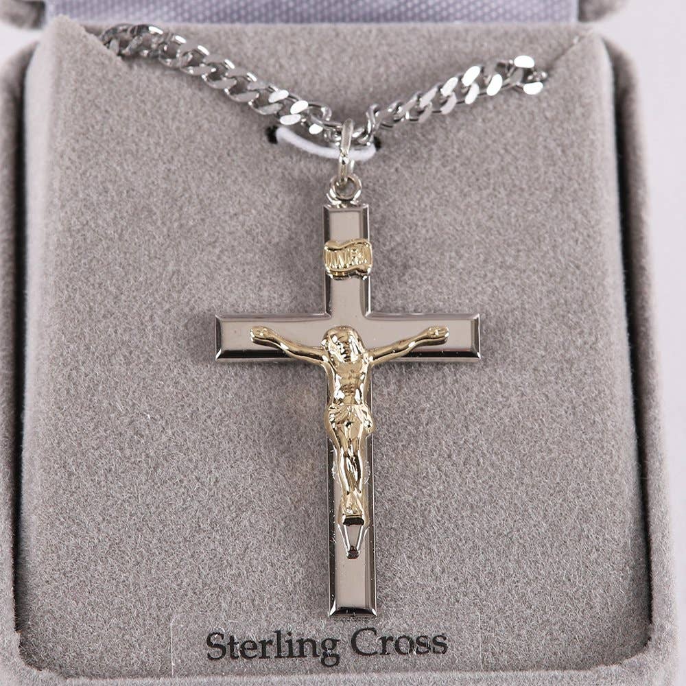 Silver crucifix necklace with gold accents on a gray cushion