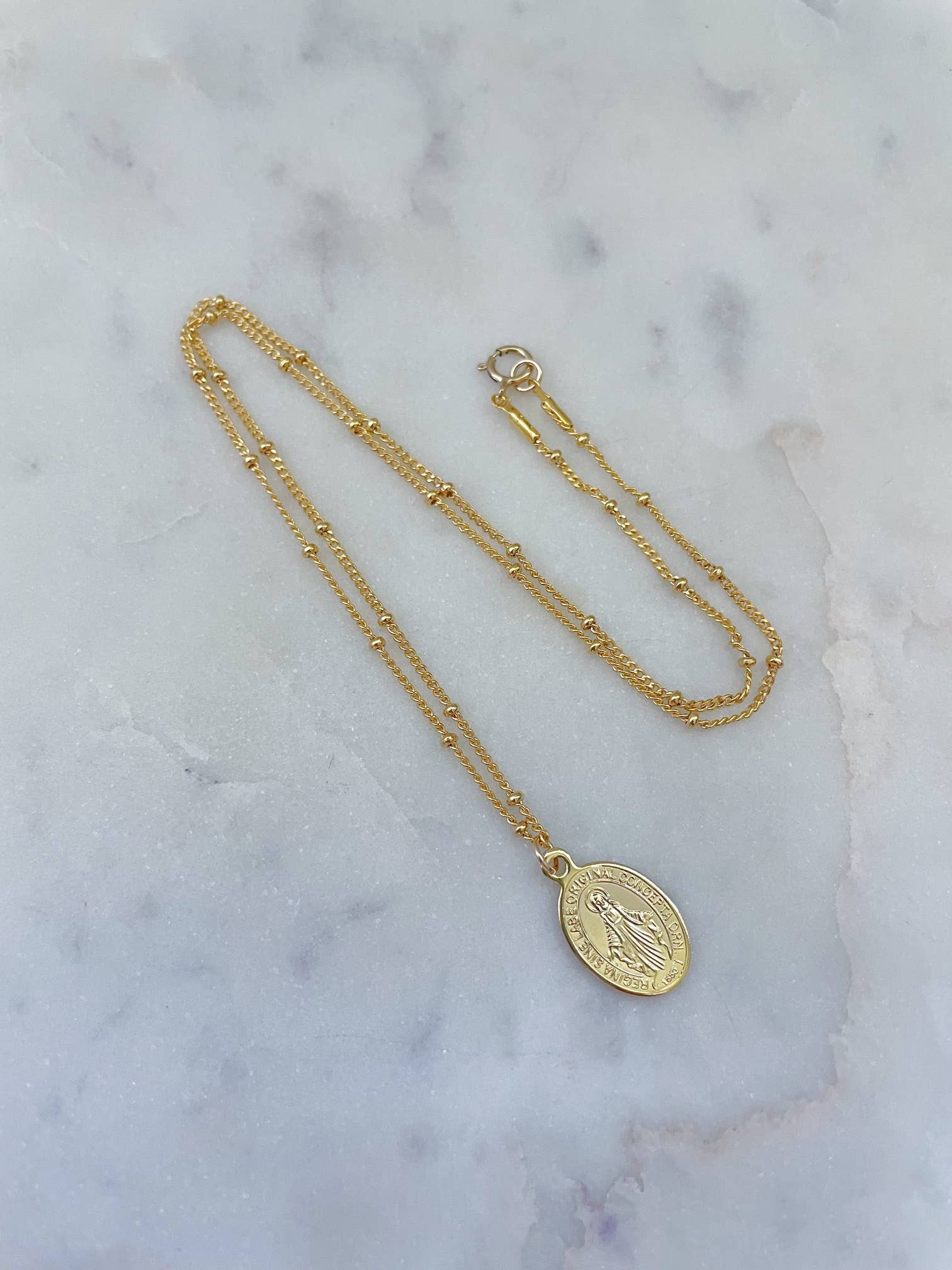 Gold necklace with a pendant on a marble surface