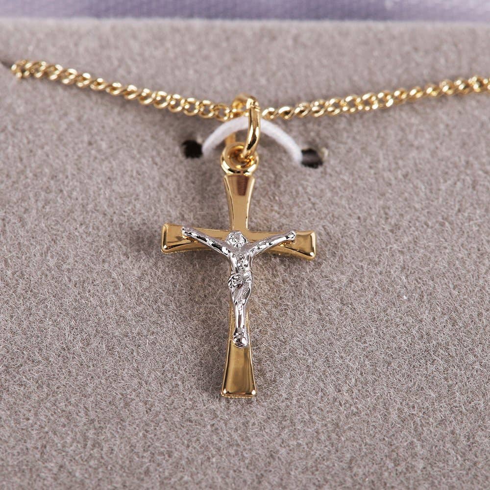 Gold and silver crucifix pendant on a chain against a gray background